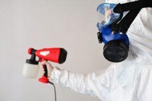 A professional cleaner using an electrostatic disinfection sprayer in an office.