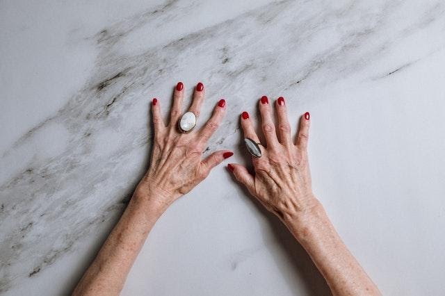 Woman's hands with red nail polish on a marble surface