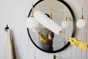 A woman dusting a mirror.