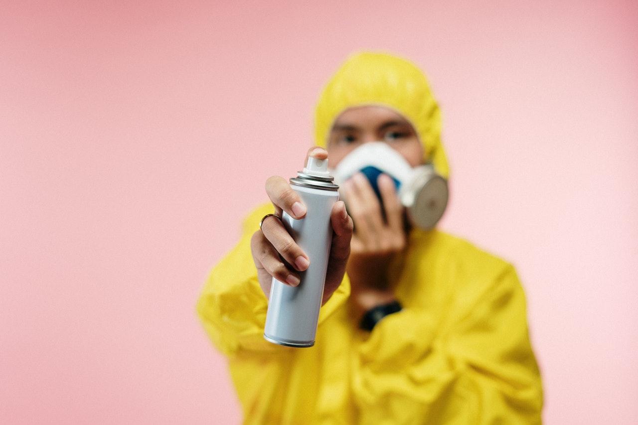 A person in protective gear holding sanitizing spray